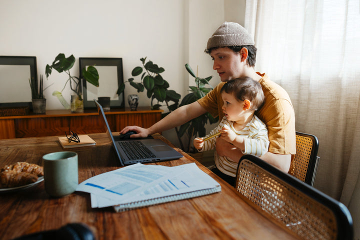Mies lapsi sylissään ruokapöydän äärellä