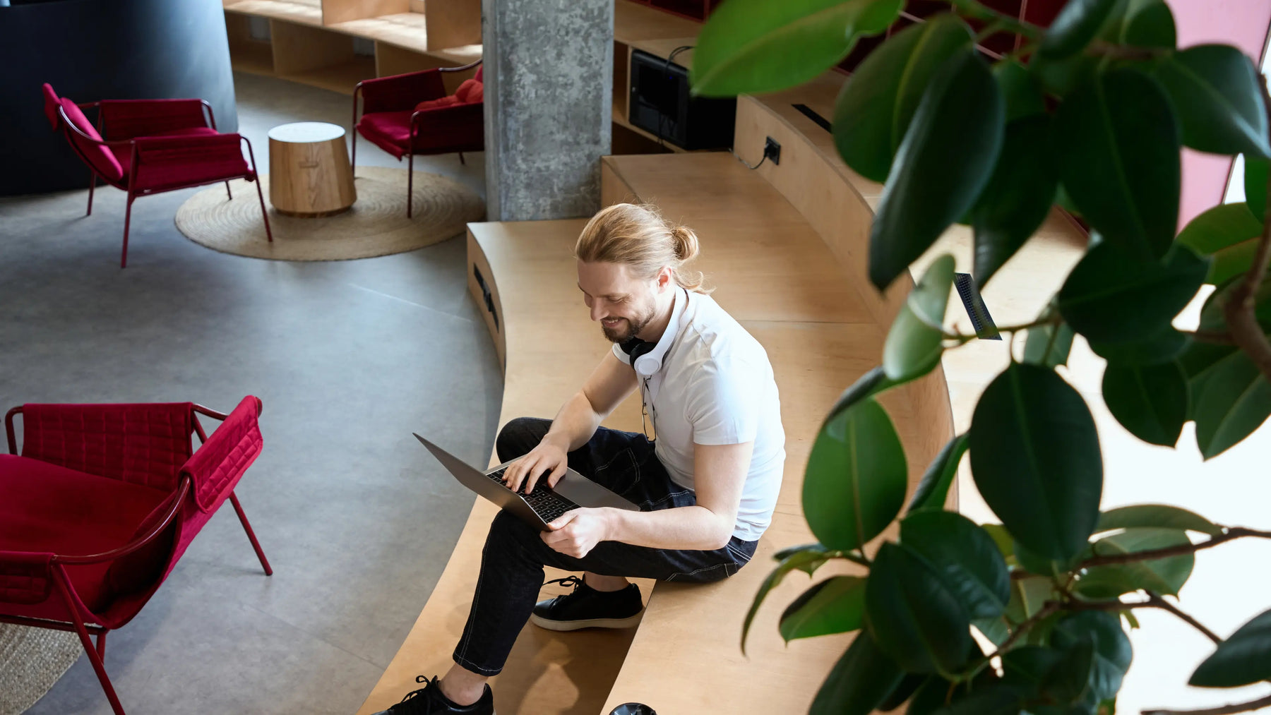Mies katsoo kannettavaa tietokonetta julkisessa tilassa